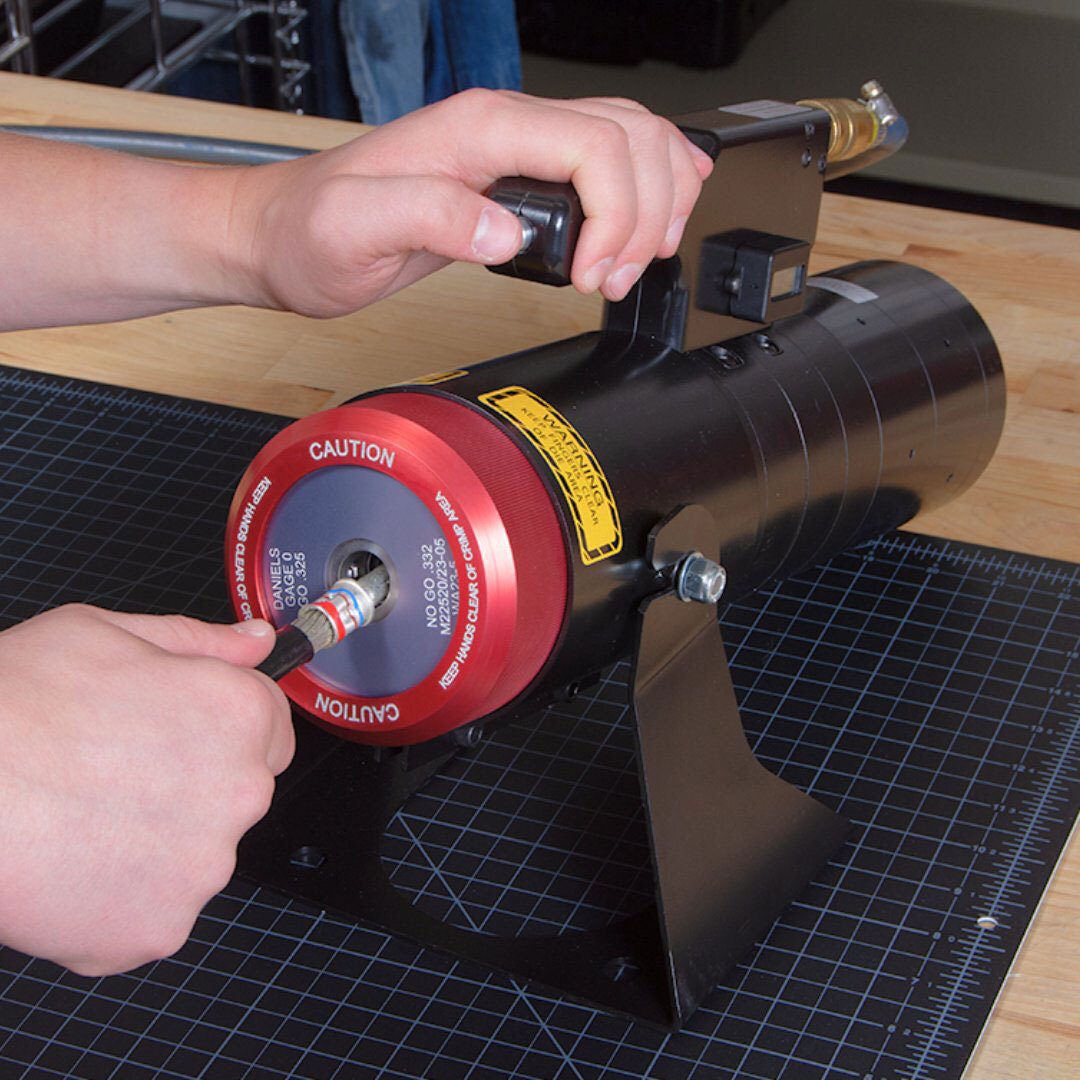 Hands operate a crimping tool on a connector.