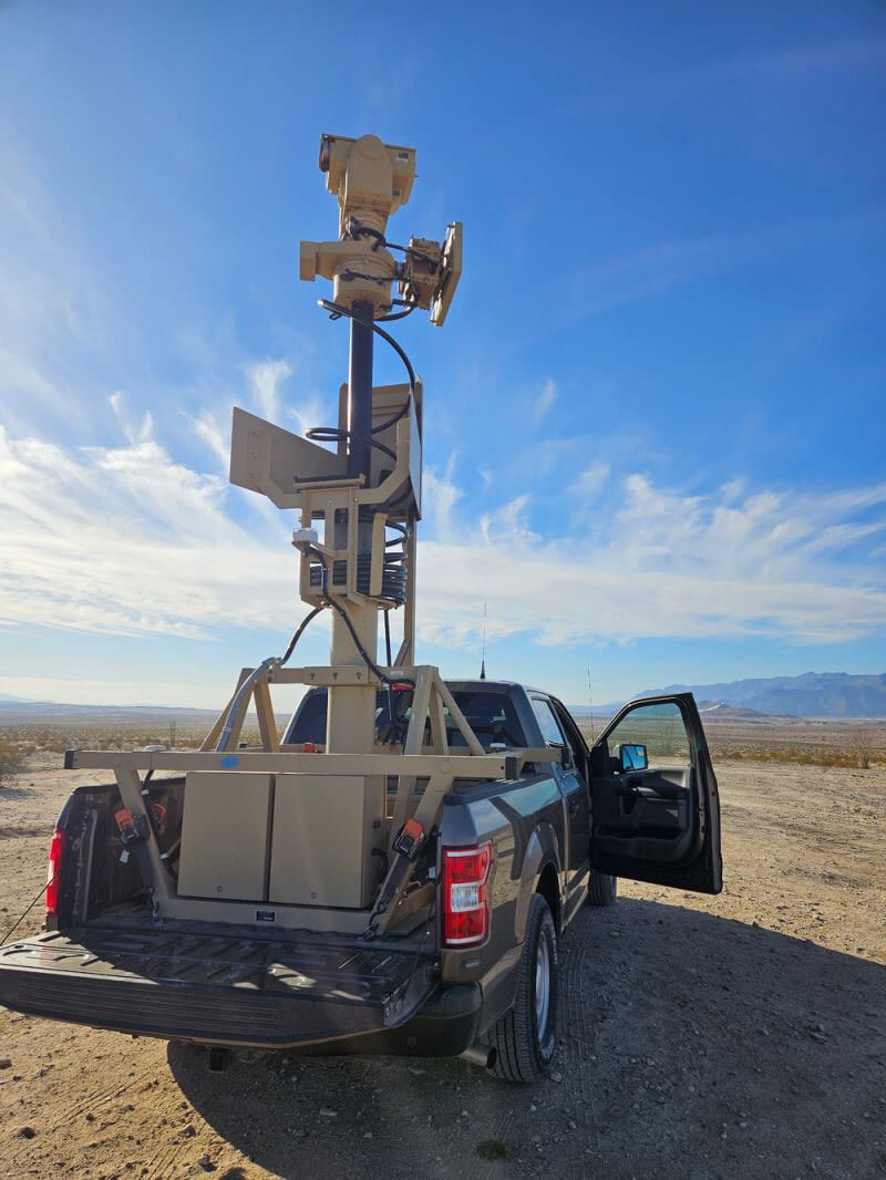 Desert pickup truck with mast-mounted sensor and comms gear.