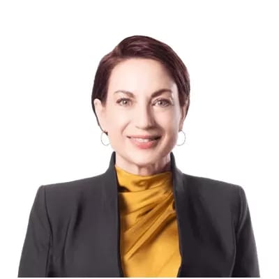 A professional woman with short dark hair and a yellow top under a black blazer smiles at the camera.