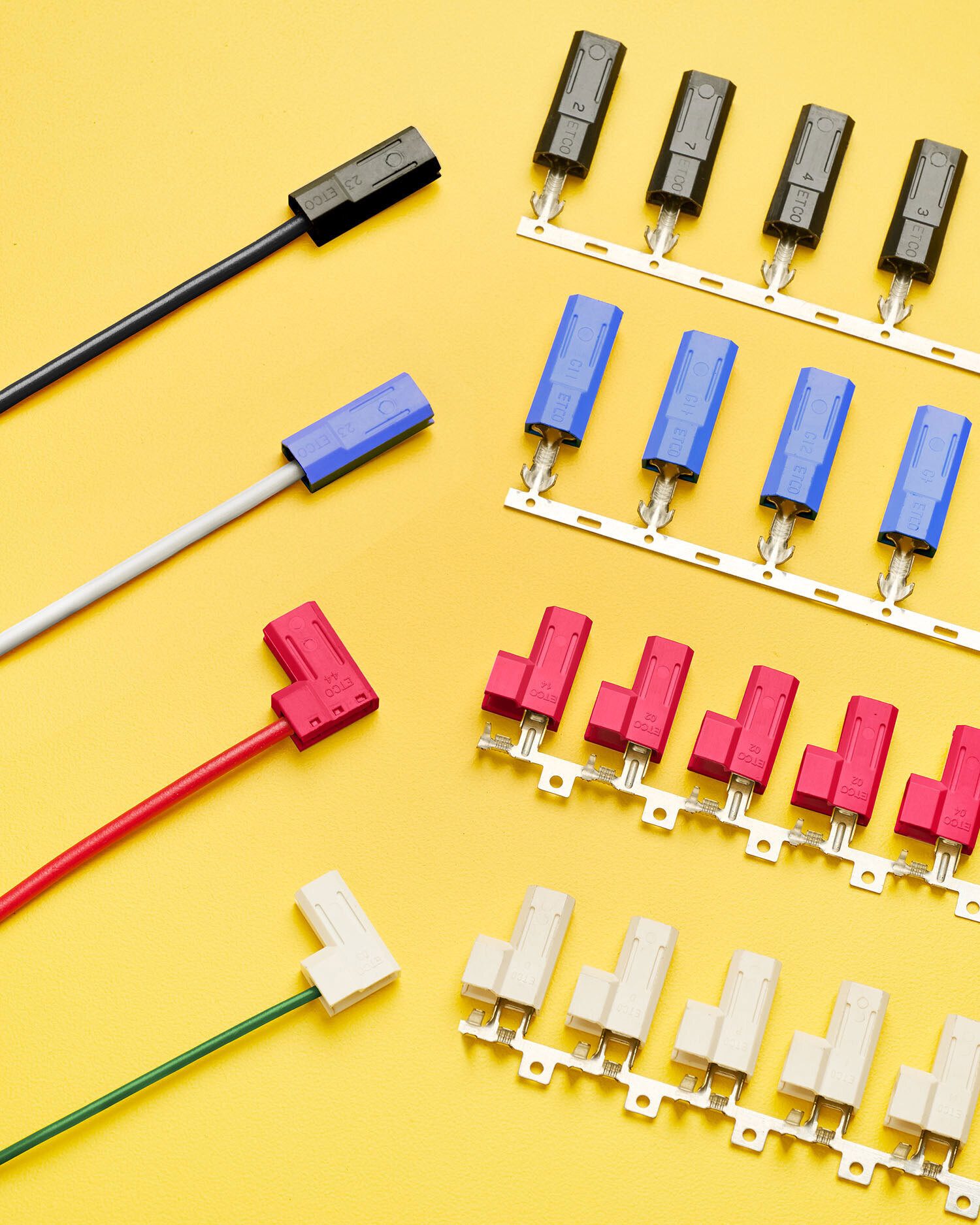 An assortment of electrical connectors, including crimp terminals and wire harnesses in black, blue, red, and white on a yellow background.