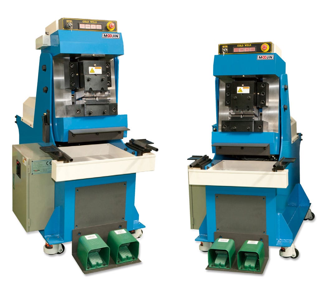 Two blue and grey industrial cold welders with foot pedal controls.