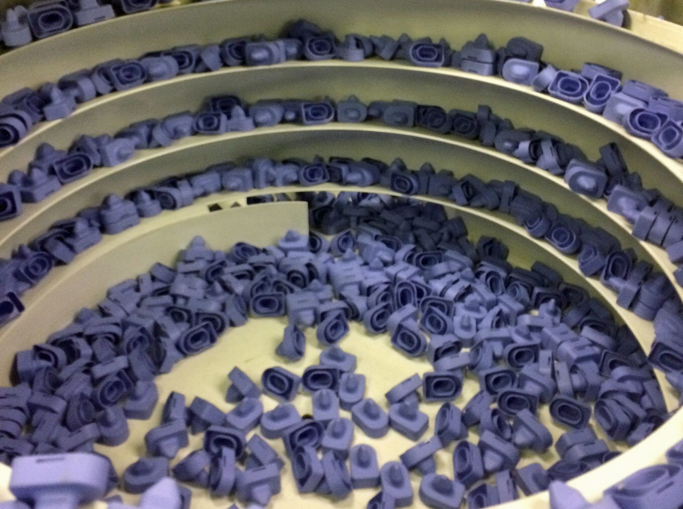Purple parts on a spiral sorter, some in rows, some piled up.