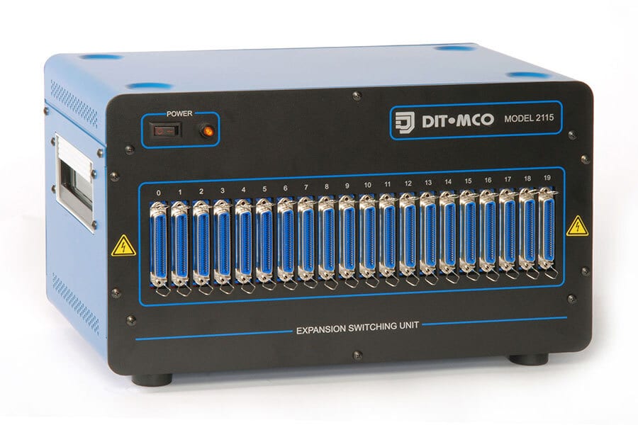 A DIT-MCO Model 2115 Expansion Switching Unit with 20 blue multi-pin connectors on its front.