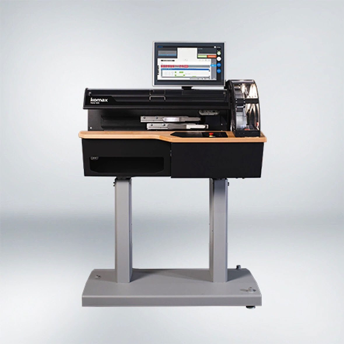 A Komax mail processing and sorting system with an integrated monitor on a stand.