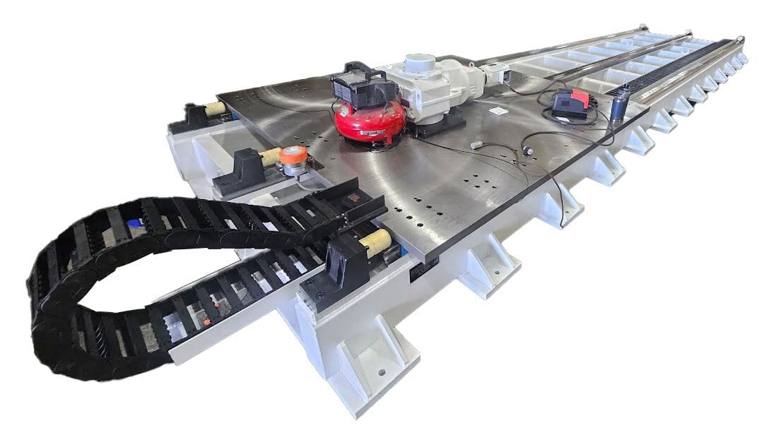 Industrial machine bed with a red motor, white gearbox, and black cable management chain.