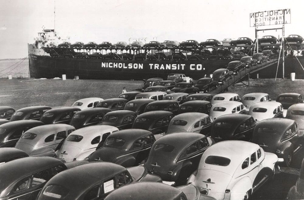 Nicholson Transit Co. ship loaded with cars at dock, more cars parked.