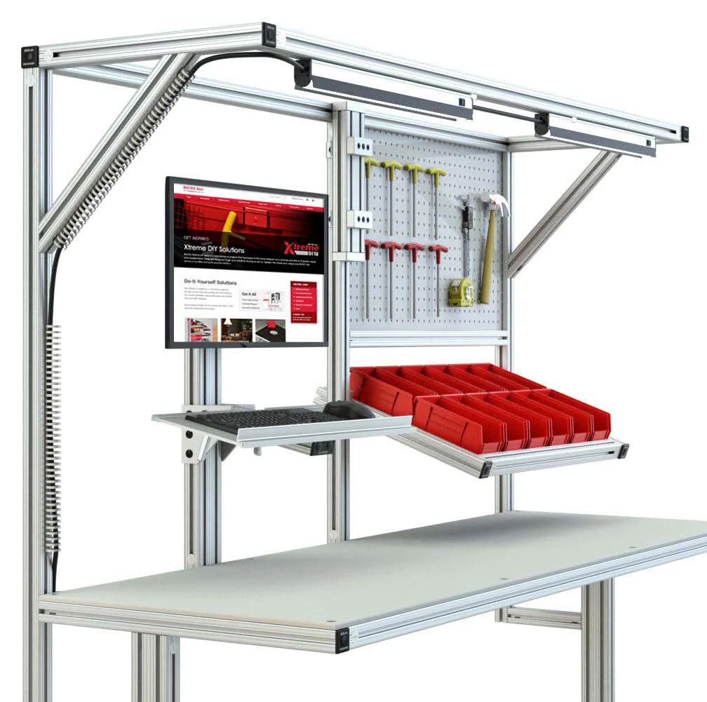 Modular workbench with aluminum frame, monitor, keyboard, pegboard tools, and red storage bins.