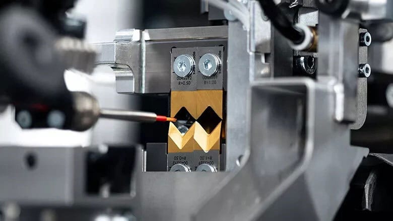 Close-up of a tool tip in a V-shaped golden die within industrial machinery.