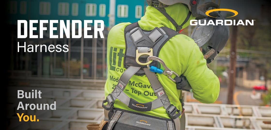 A construction worker wearing a Guardian Defender Harness and hard hat, seen from behind on a job site.