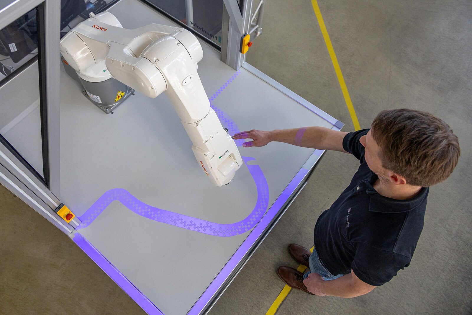 Man interacts with KUKA robot and projected safety zone.