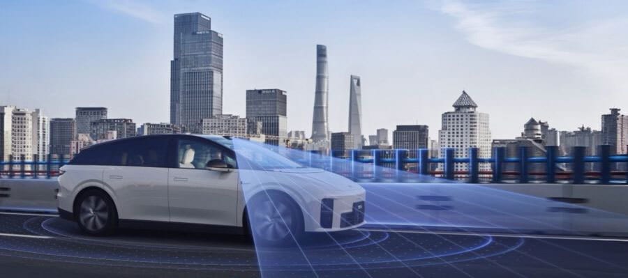 White futuristic car with blue autonomous driving overlay on a city road with skyline.