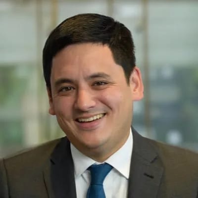 Smiling man in a suit with a blue tie.