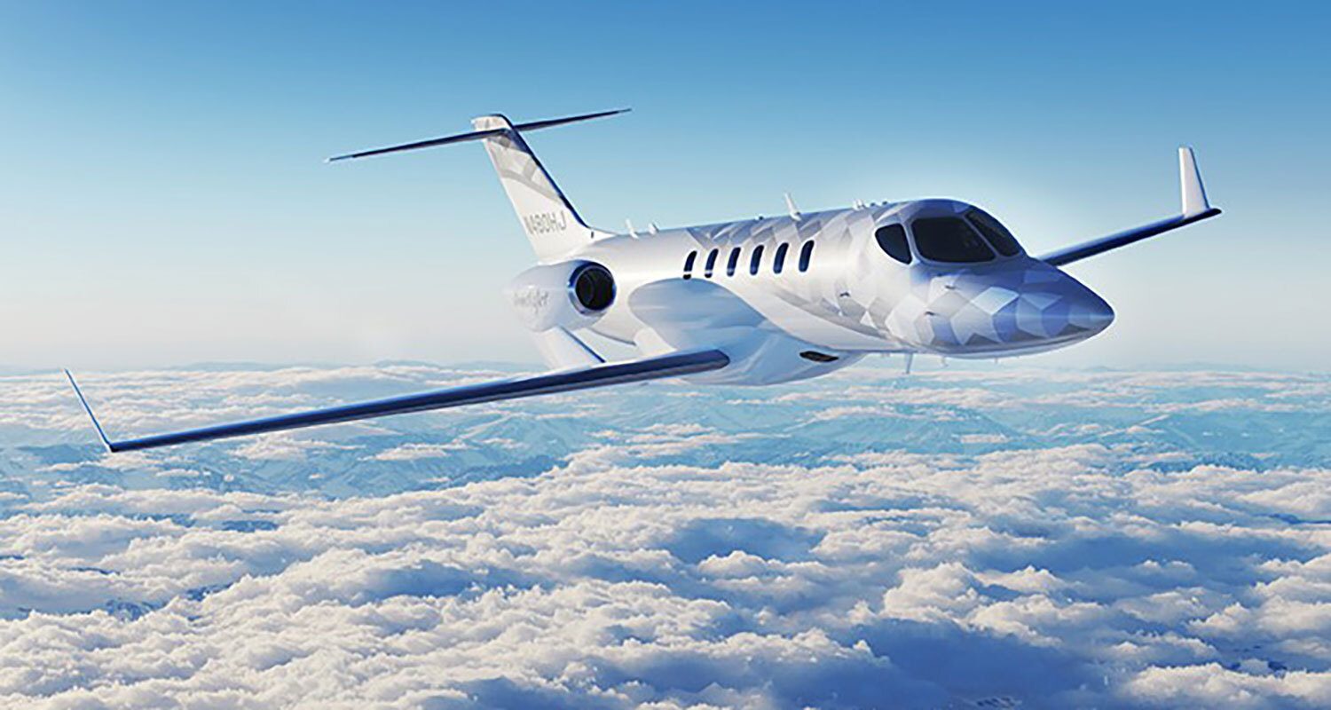 A private jet with a camouflage nose flying over clouds and mountains.