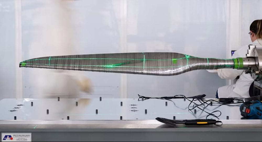 A technician uses green lasers to measure a composite blade.