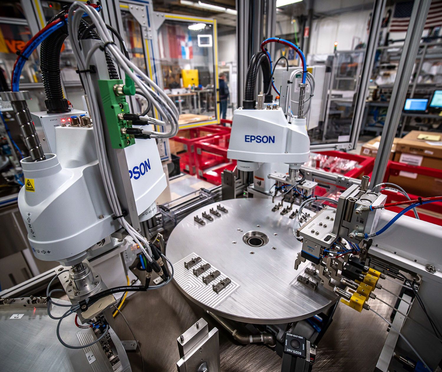 Automated manufacturing line with two Epson robots assembling small components.