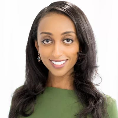 Headshot of a smiling woman with dark hair wearing a green top.