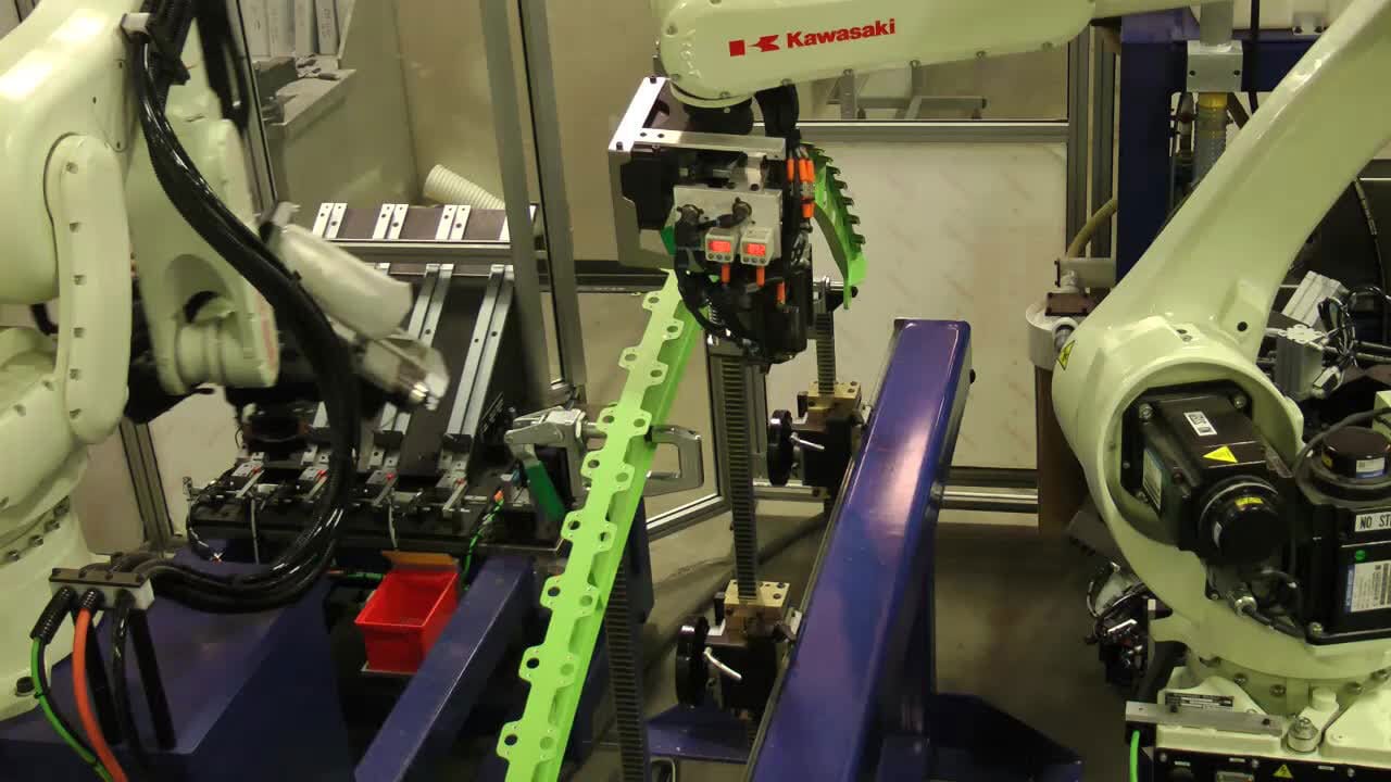 Multiple industrial robots, including a Kawasaki, operate a green conveyor in a factory setting.