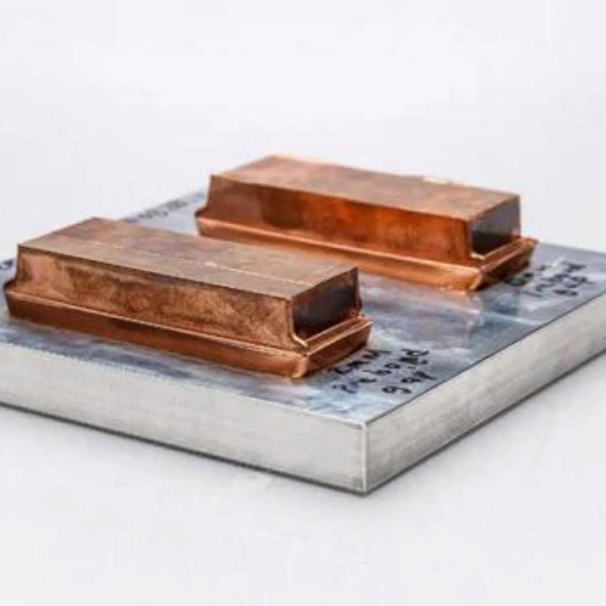Two rectangular copper components on a brushed metal plate.