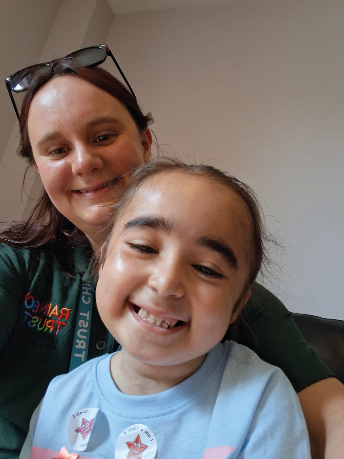 Smiling woman and happy child in a selfie, woman wearing a Rainbow Trust shirt.