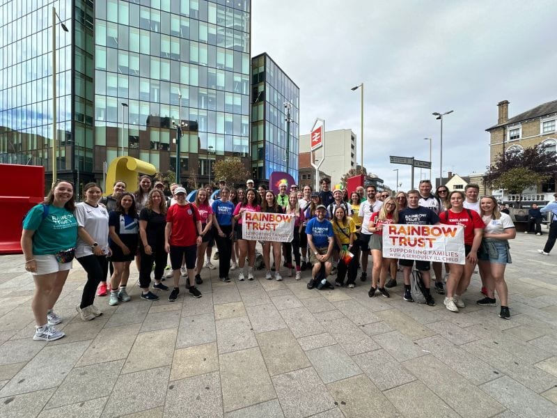 A large group holds "Rainbow Trust" banners supporting families with seriously ill children.