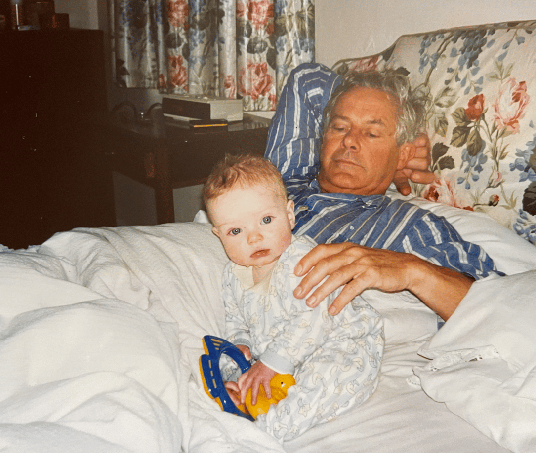 Grandfather and grandchild in bed, baby holding toy.