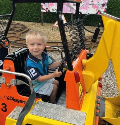Smiling blonde boy in a toy digger.