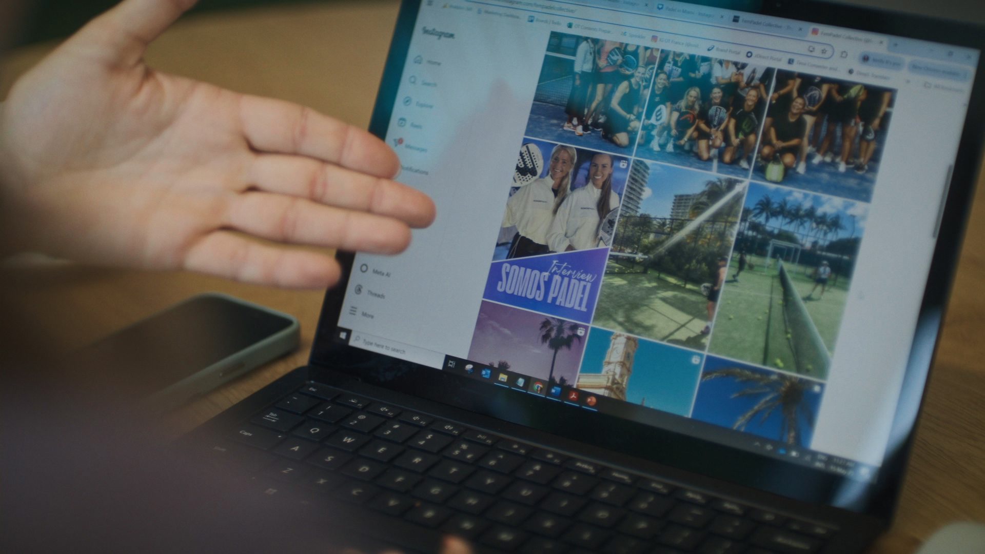 Hand pointing at laptop showing padel Instagram "SOMOS PADEL Interview".