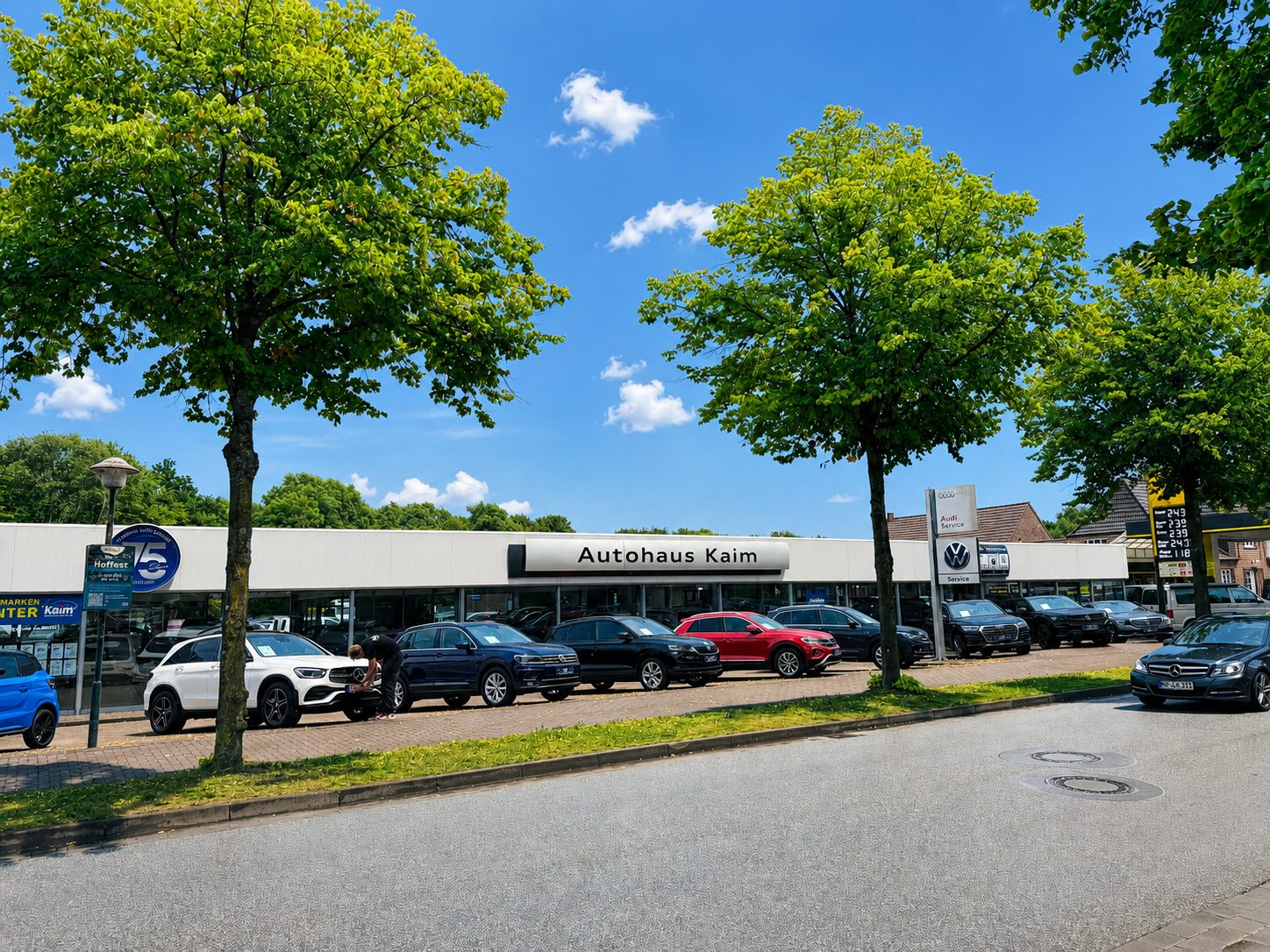 Exterior of Autohaus Kaim car dealership with various cars parked outside on a sunny day.