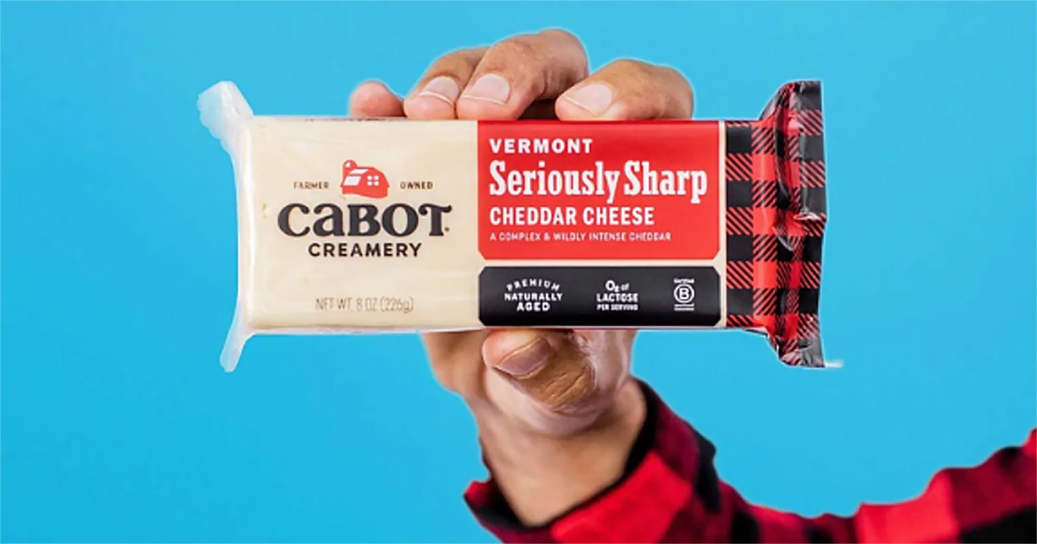 Man holding Cabot Cheese Bar against sky blue background