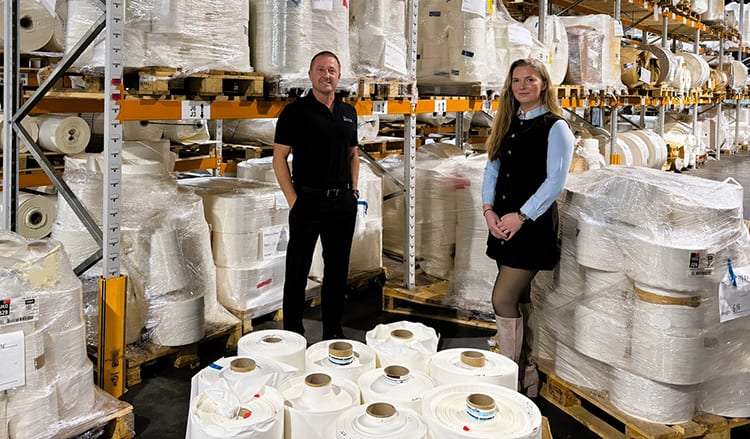 Mark Thompson and Marci Clarke with rolls of labels in warehouse.  