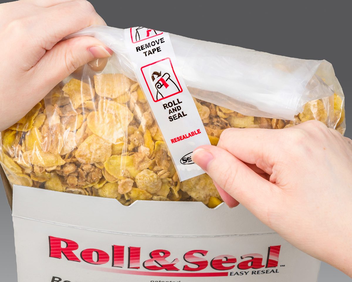 Hands opening a resealable bag of cereal inside a box, showing 'Roll & Seal' instructions.