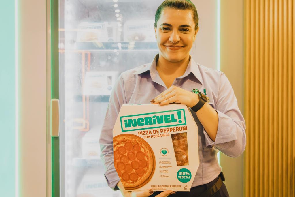 Woman holding frozen pizza with plant-based ingredients