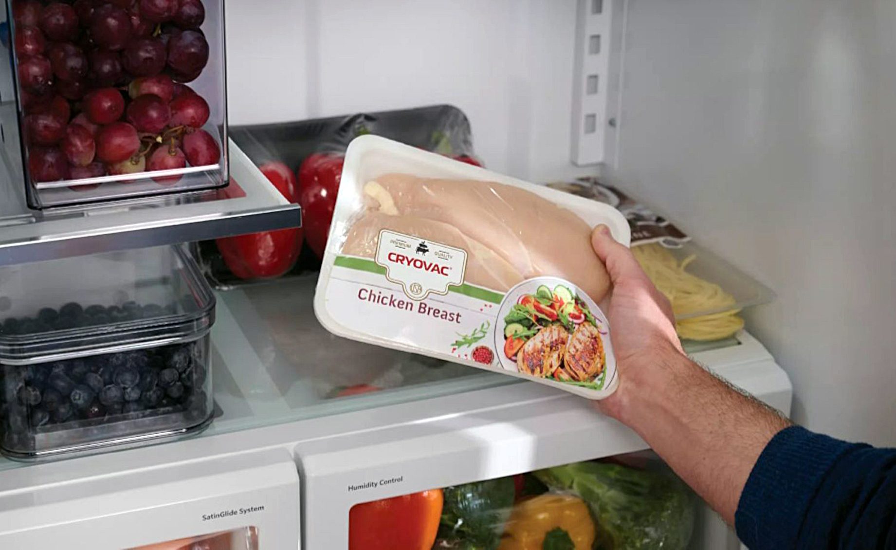 Person holding chicken breast in SEE CRYOVAC packaging