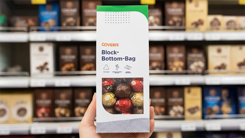 Hand in a grocery store holding new Coveris bag filled with chocolates