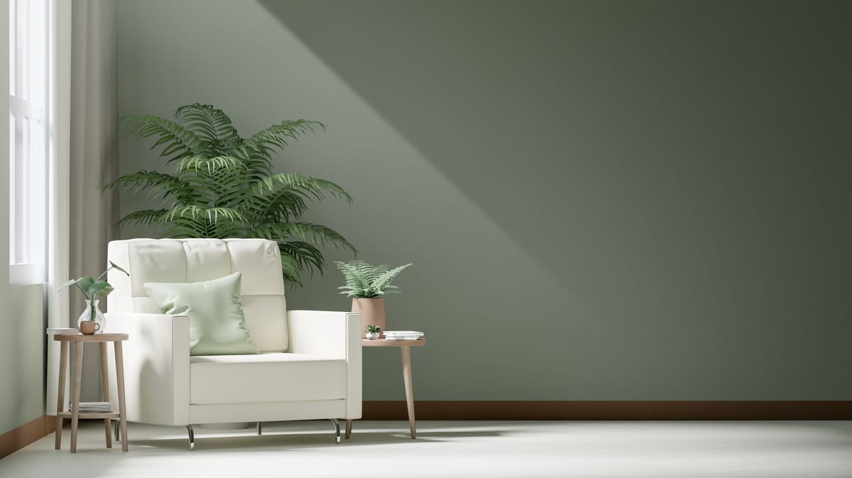 A cozy, modern living room corner with a cream armchair, green plants, and a sunlit wall.