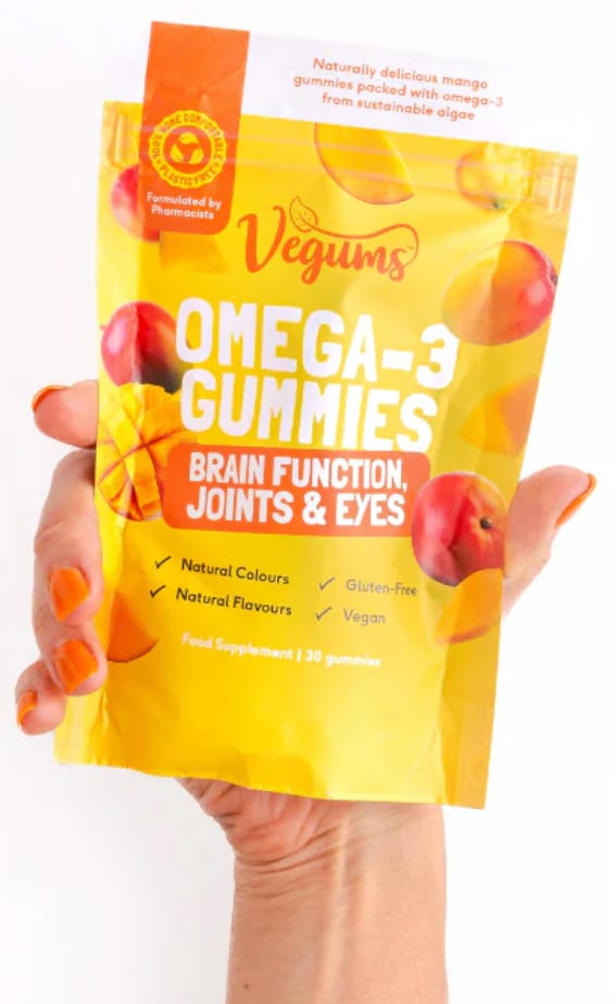 Hand holding up Vegums pouch against white background
