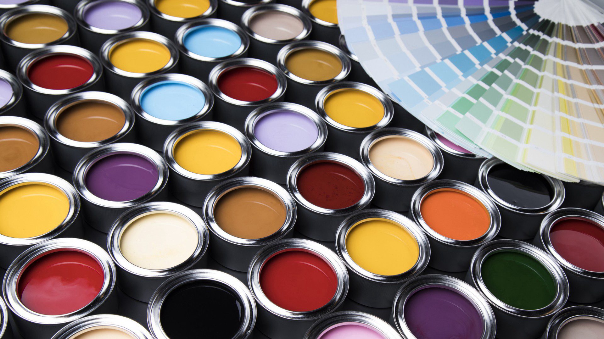 An assortment of open paint cans in various vibrant colors, alongside a color swatches fan.