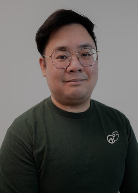 Smiling man with glasses in a dark green shirt with a logo.