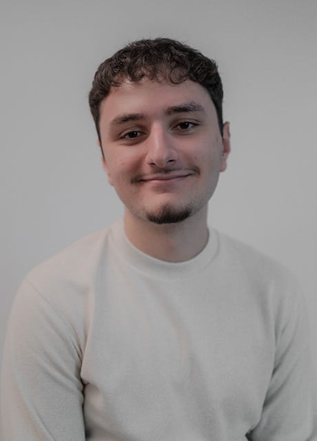 Smiling man with curly hair and facial hair.