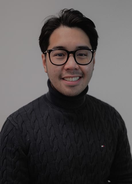 Smiling man with glasses wearing a dark cable-knit turtleneck.