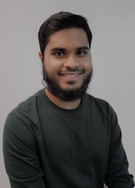 Smiling man with a beard and dark long-sleeved shirt.