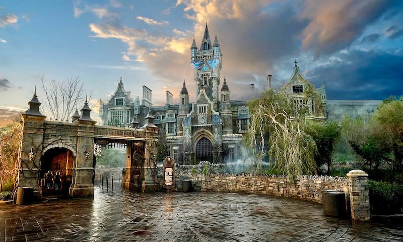 Gothic castle and ornate gate under a dramatic cloudy sky, with a wet cobblestone courtyard.