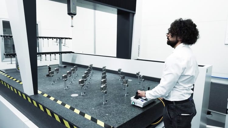 Engineer operating a large CMM to measure components in a clean room.
