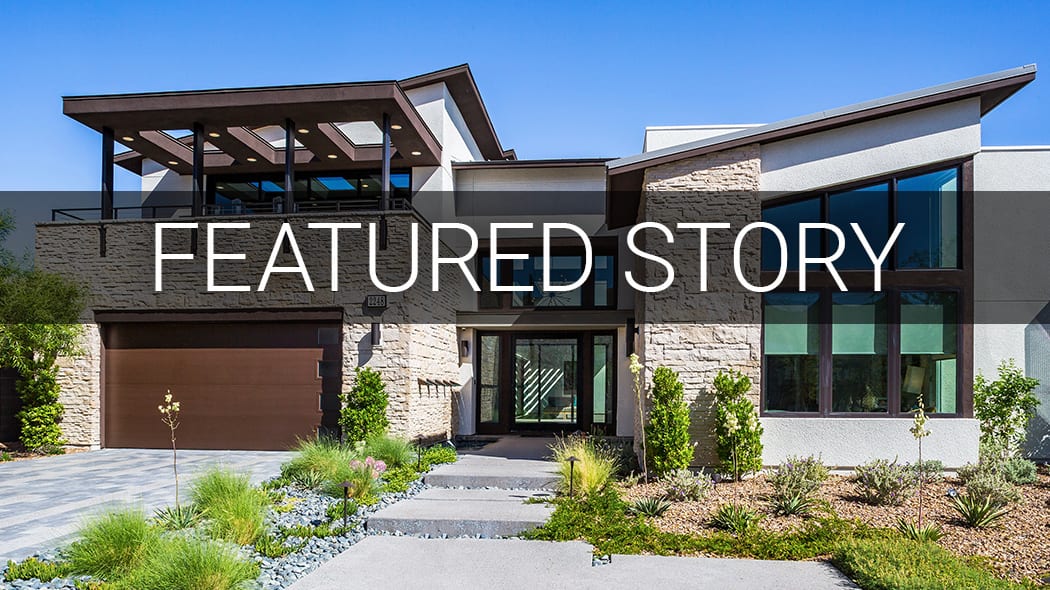 Modern, multi-level house with large windows, garage, and landscaped yard under a clear blue sky.