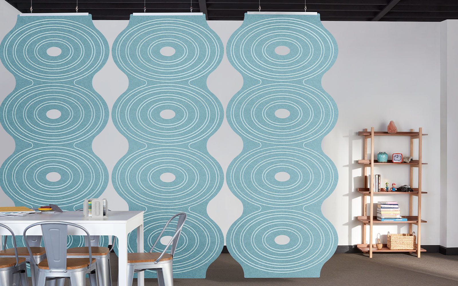 Blue ripple-patterned acoustic panels, white table with chairs, and wooden shelf in an office.