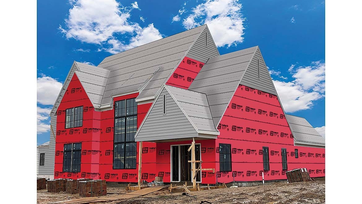 House under construction with red house wrap and gray metal roof.