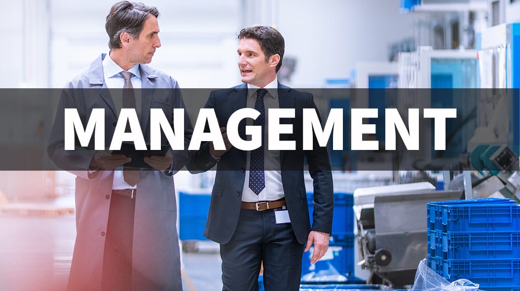 Two businessmen in a factory with "MANAGEMENT" text overlaid.