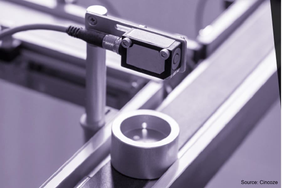 Industrial sensor observing a cylindrical object on a conveyor belt.