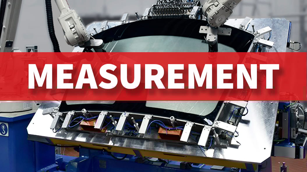 Robotic arms measuring a car windshield, with "MEASUREMENT" text on a red banner.