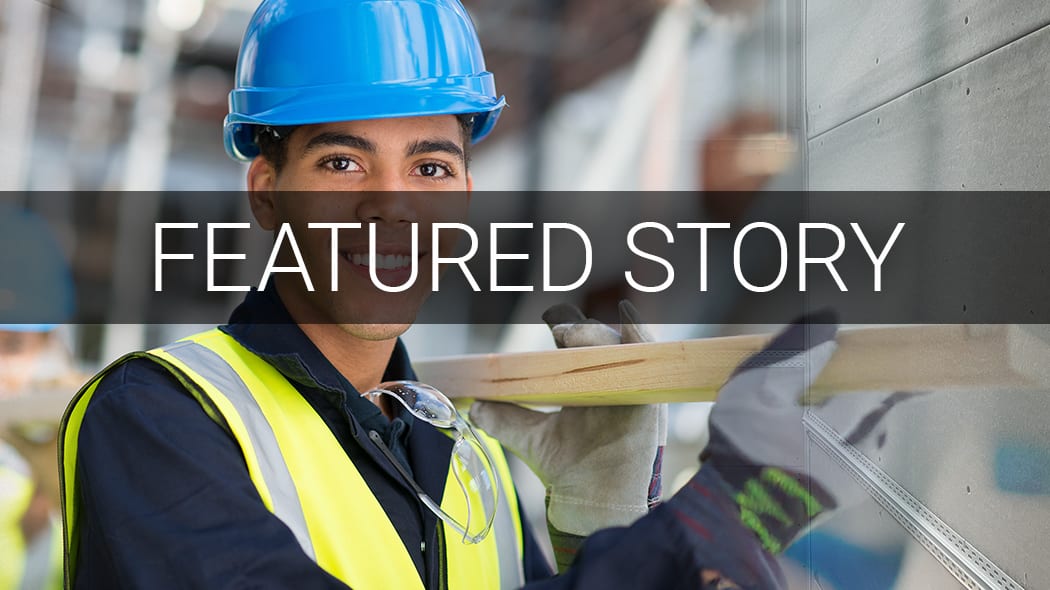 Young man in hard hat and safety vest smiling, carrying lumber. Text: "FEATURED STORY".